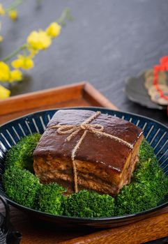 Dong Po Rou (Dongpo pork meat) in a beautiful blue plate with green broccoli vegetable, traditional festive food for Chinese new year cuisine meal, close up.