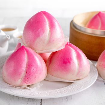 Pink Chinese peach birthday bun food named Longevity peach shoutao on white table background.