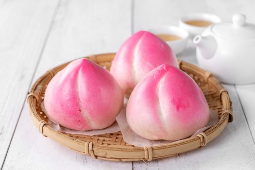 Pink Chinese peach birthday bun food named Longevity peach shoutao on white table background.