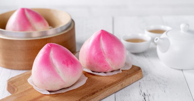 Pink Chinese peach birthday bun food named Longevity peach shoutao on white table background.