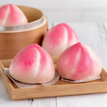 Pink Chinese peach birthday bun food named Longevity peach shoutao on white table background.