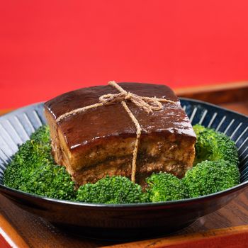 Dong Po Rou (Dongpo pork meat) in a beautiful blue plate with green broccoli vegetable, traditional festive food for Chinese new year cuisine meal, close up.