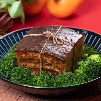 Dong Po Rou (Dongpo pork meat) in a beautiful blue plate with green broccoli vegetable, traditional festive food for Chinese new year cuisine meal, close up.