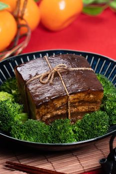 Dong Po Rou (Dongpo pork meat) in a beautiful blue plate with green broccoli vegetable, traditional festive food for Chinese new year cuisine meal, close up.