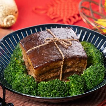 Dong Po Rou (Dongpo pork meat) in a beautiful blue plate with green broccoli vegetable, traditional festive food for Chinese new year cuisine meal, close up.