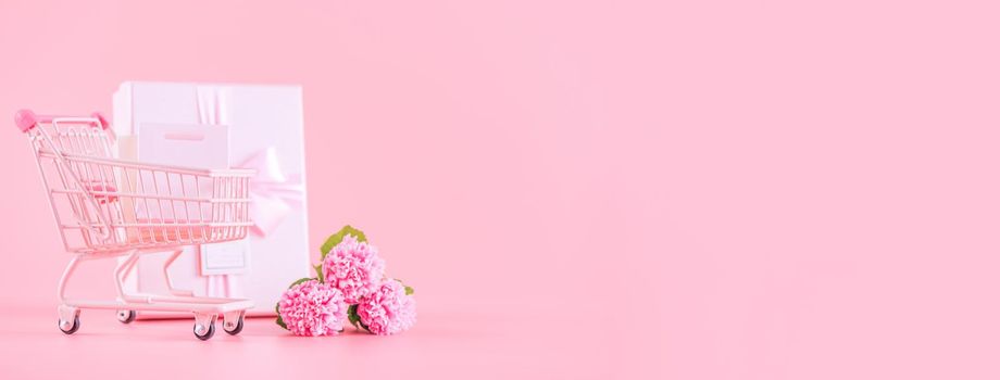 Mother's Day holiday gift design concept, pink carnation flower bouquet with wrapped gift box isolated on pink background, copy space.