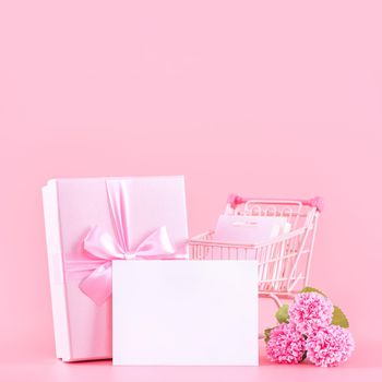 Mother's Day holiday gift design concept, pink carnation flower bouquet with wrapped gift box isolated on pink background, copy space.