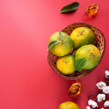 Top view of fresh ripe tangerine mandarin orange with fresh leaves on red table background for Chinese lunar new year fruit concept, the Chinese word means spring.