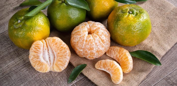 Fresh green tangerine mandarin orange with fresh leaves on dark wooden table background harvest concept.