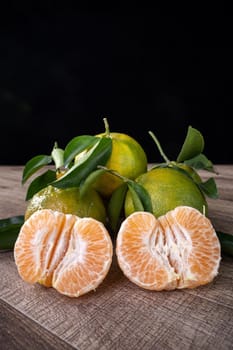 Fresh green tangerine mandarin orange with fresh leaves on dark wooden table background harvest concept.