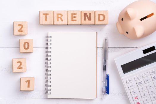 2021 financial trend design concept with blank notebook, piggy bank, calculator and wooden block.