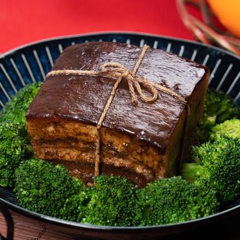 Dong Po Rou (Dongpo pork meat) in a beautiful blue plate with green broccoli vegetable, traditional festive food for Chinese new year cuisine meal, close up.