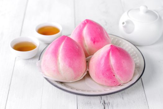 Pink Chinese peach birthday bun food named Longevity peach shoutao on white table background.