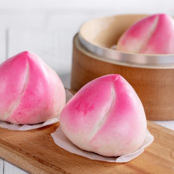 Pink Chinese peach birthday bun food named Longevity peach shoutao on white table background.
