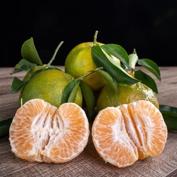 Fresh green tangerine mandarin orange with fresh leaves on dark wooden table background harvest concept.