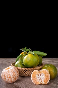 Fresh green tangerine mandarin orange with fresh leaves on dark wooden table background harvest concept.