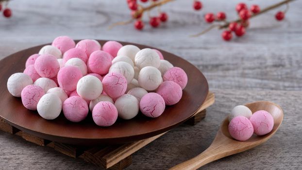 Raw red and white tangyuan glutinous rice dumpling balls on wooden table background for Winter solstice festival food.