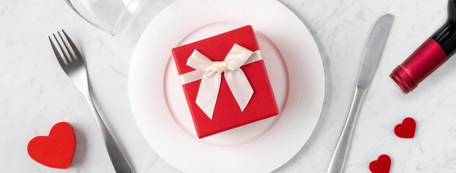 Empty white plate with tableware, ribbon, gift and roses for Valentine's Day special holiday dating meal concept.