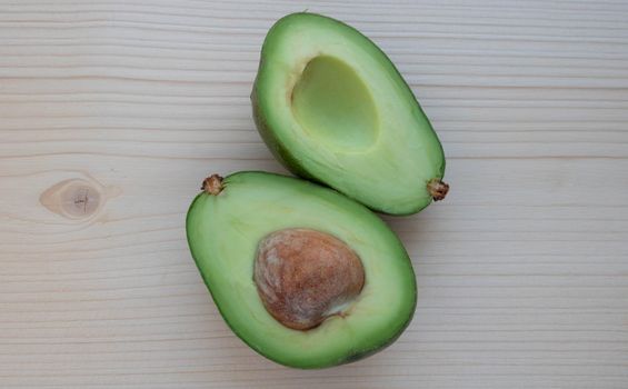 Slices of ripe avocado lie on a light cutting board.