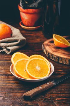 Slices of orange on white plate in rustic setting