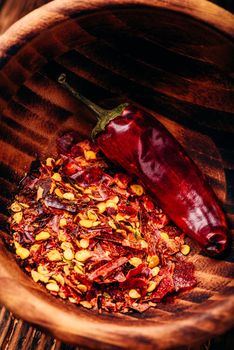 Flakes of ground red chili pepper in wooden bowl