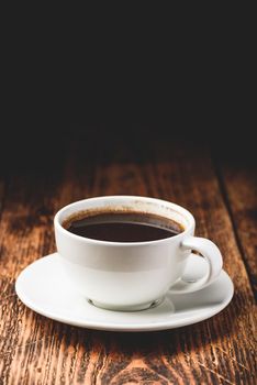 Black coffee in white cup over wooden surface