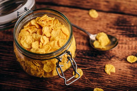 Jar of corn flakes for breakfast on wooden surface