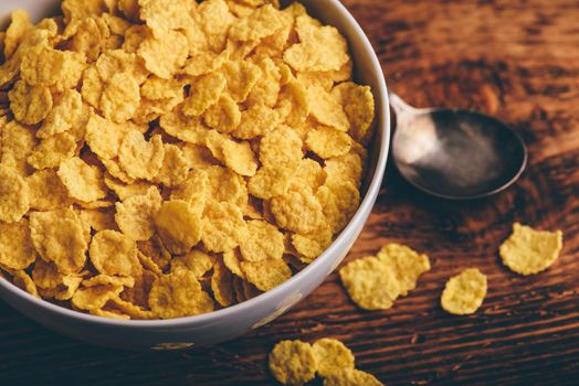 White bowl of corn flakes on a rustic wooden surface