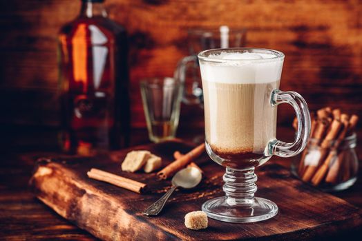 Irish coffee with cinnamon on wooden surface