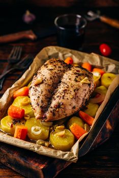 Seasoned chicken breast baked in oven with vegetables on baking sheet