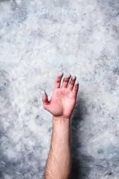 Man hand covered with paint on gray concrete wall background