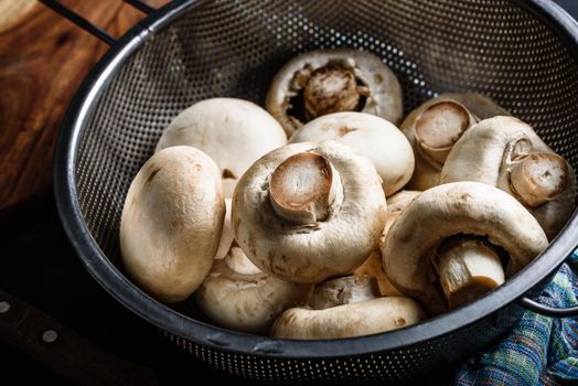 Fresh white button mushrooms in metal colander