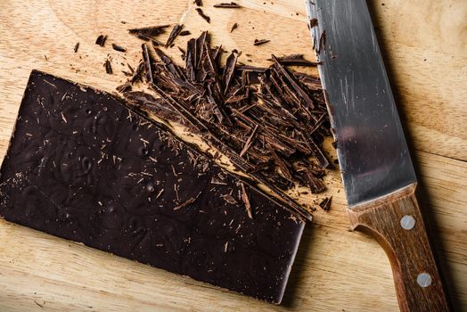 Crushed dark chocolate bar with rustic knife on cutting board