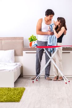 Young woman doing ironing for her husband
