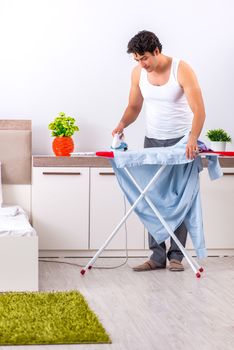 Young man ironing in the bedroom 