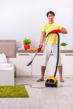 Young handsome man cleaning in the bedroom