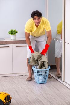 Young handsome man cleaning in the bedroom
