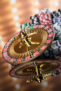 Poker Chips on gaming table, roulette wheel in motion, casino background