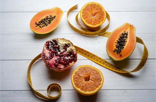 Some fruits and a tape measure on a white wooden table