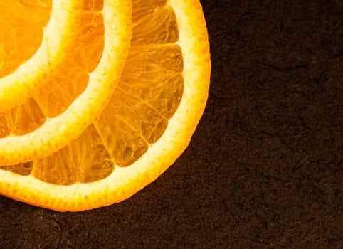 Part of orange slices on a dark background. Place for your text