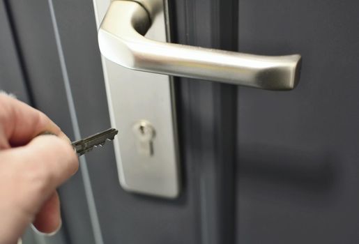 A hand holding a key for inserting a key into the door lock. Unlocking the security lock.