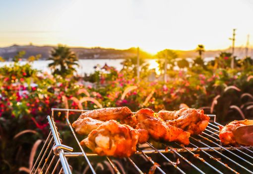 Cooking chicken skewers on the grill in the garden at sunset