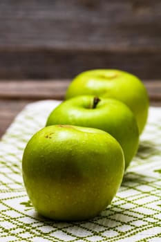 Detail on ripe green apples on wooden table.