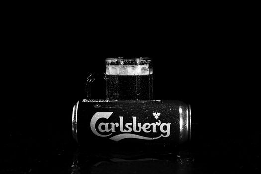 Can of Carlsberg beer and beer glass on dark background. Illustrative editorial photo shot in Bucharest, Romania, 2021