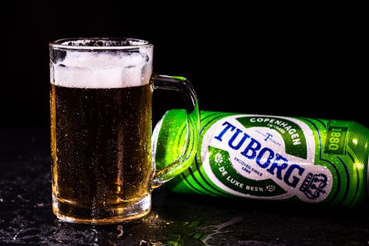 Can of Tuborg beer and beer glass on dark background. Illustrative editorial photo shot in Bucharest, Romania, 2021