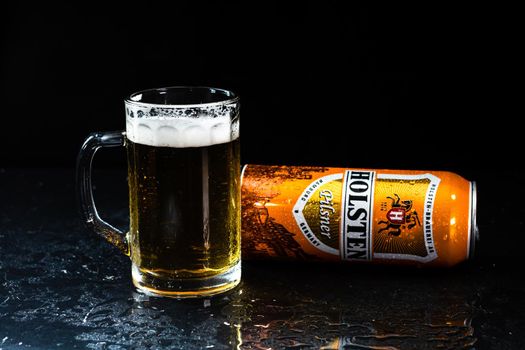 Can of Holsten beer and beer glass on dark background. Illustrative editorial photo shot in Bucharest, Romania, 2021