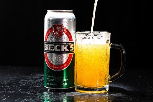 Can of Beck`s or Becks beer and beer glass on dark background. Illustrative editorial photo shot in Bucharest, Romania, 2021