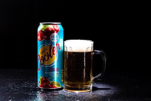 Can of Ursus Cooler beer and beer glass on dark background. Illustrative editorial photo shot in Bucharest, Romania, 2021