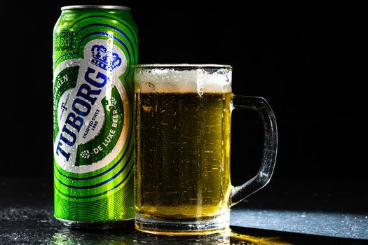 Can of Tuborg beer and beer glass on dark background. Illustrative editorial photo shot in Bucharest, Romania, 2021