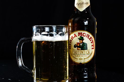 Can of Birra Morreti beer and beer glass on dark background. Illustrative editorial photo shot in Bucharest, Romania, 2021